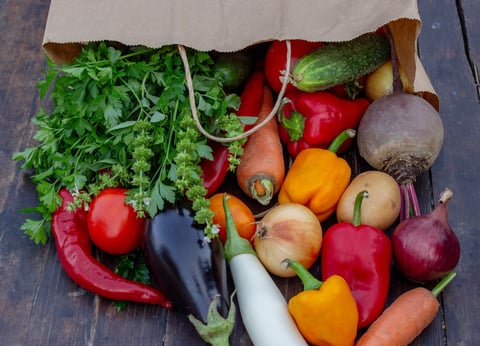 fresh vegetables on a wooden background in a paper bag